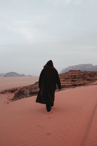 Rear view of woman walking on sand at desert