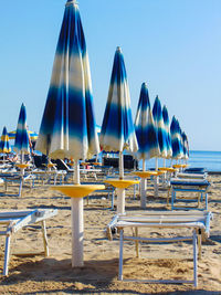 Deck chairs on beach against clear blue sky