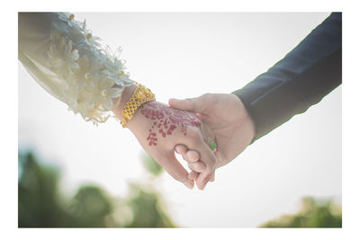 Cropped hand of couple holding hands during wedding