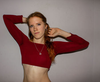 Portrait of beautiful young woman standing against wall