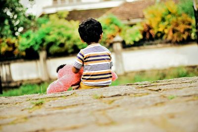 Rear view of boy sitting outdoors