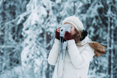 Woman with umbrella standing in snow