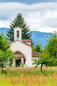 Built structure by trees and building against sky