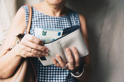 Midsection of woman holding inserting money from purse
