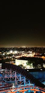 Illuminated cityscape by sea against sky at night