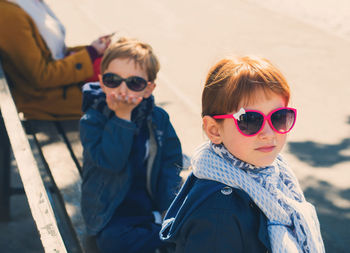 Portrait of siblings wearing sunglasses sitting on bench