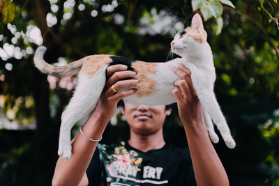 Young man holding cat standing outdoors