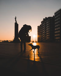 Silhouette of a woman standing on a square during sunset