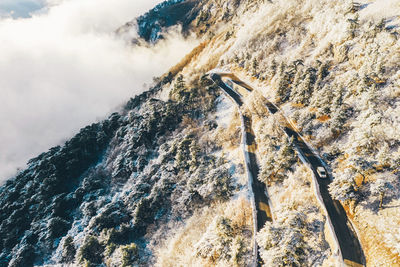 Aerial view on serpentine road in snowy winter forest at the mountain.