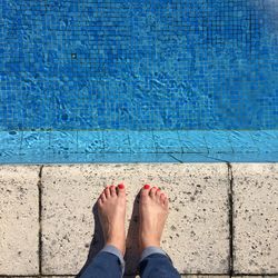 Low section of young woman standing at poolside