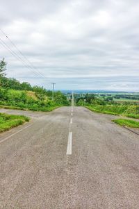 Road amidst field against sky