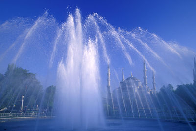 Low angle view of fountain in city against sky