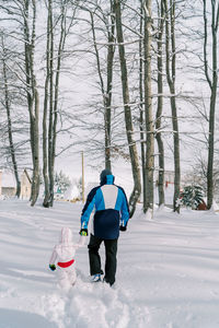 Rear view of man skiing on snow covered field