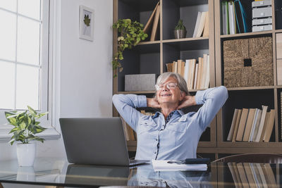 Young woman using mobile phone while sitting on table