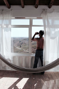 Woman standing by window at home