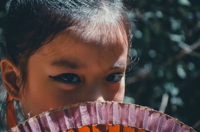 Close-up portrait of cute girl with hand fan