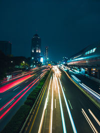 Light trails on road amidst buildings in city at night