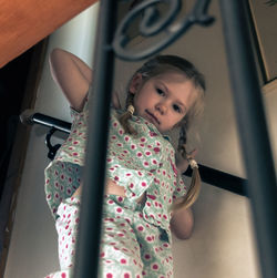 Low angle portrait of girl wearing pajamas standing on steps at home