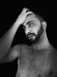 Shirtless man taking shower against black background