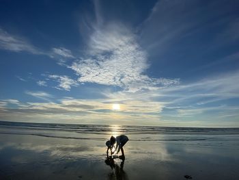 People on beach against sky during sunset