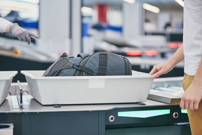 Midsection of man picking suitcase from conveyor belt