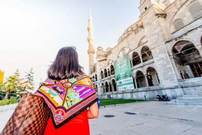 Rear view of woman standing against building