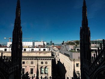 Duomo di milano and buildings in city against clear blue sky