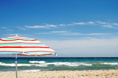 Lifeguard hut on beach against blue sky