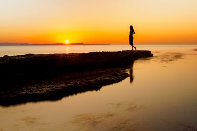Silhouette person on beach against sky during sunset