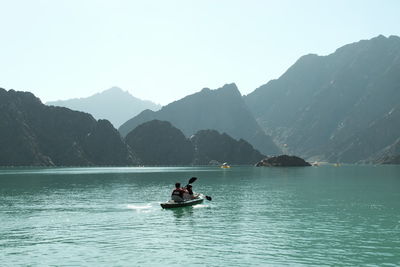 People on boat in lake against sky