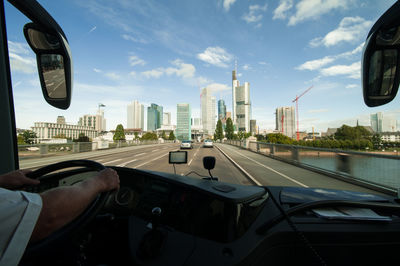 Man driving car in city against sky