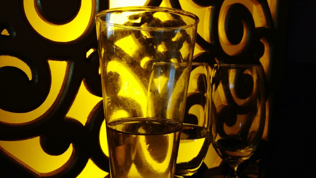 indoors, close-up, drink, still life, yellow, table, no people, glass - material, refreshment, food and drink, freshness, focus on foreground, arrangement, design, transparent, pattern, variation, text, reflection, art and craft