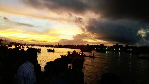 Silhouette people by sea against sky during sunset