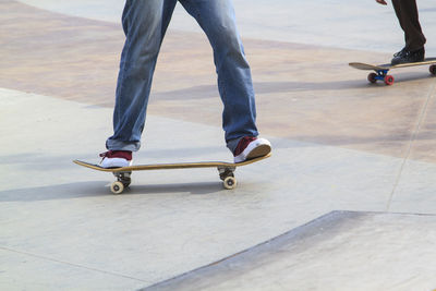 Low section of people skateboarding on footpath