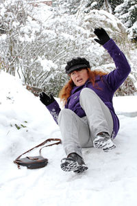 Full length of woman with arms raised in snow