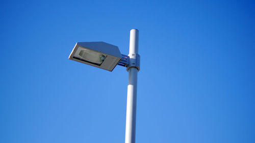 Low angle view of telephone pole against clear blue sky