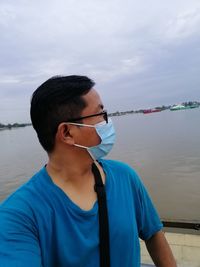 Portrait of young man standing in sea against sky