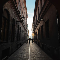 Rear view of man walking on street amidst buildings in city