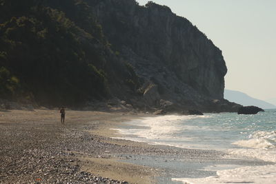 Scenic view of sea by mountain against sky