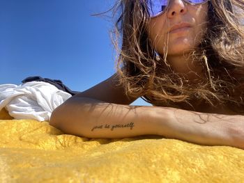 Low angle portrait of woman lying down against sky