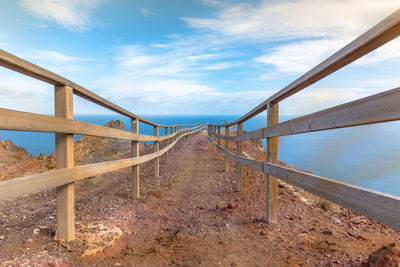 Walkway leading to sea against sky