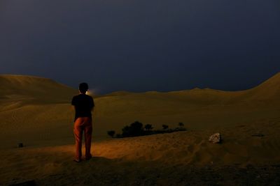 Rear view of man standing on landscape at night