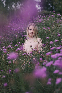 Woman standing on purple flowering plants on field