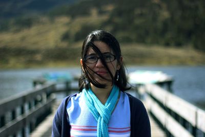 Portrait of woman standing on pier over lake