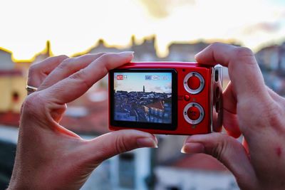 Cropped hands photographing town through camera