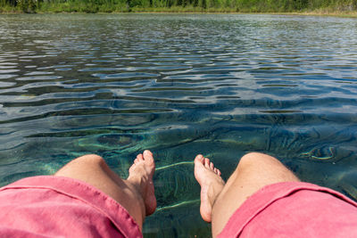 Low section of man relaxing at lake
