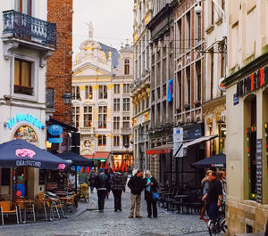 People walking on street amidst buildings in city