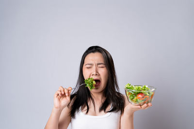 Portrait of woman eating food against white background