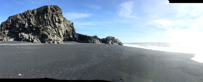 Rock formations on beach against sky