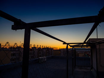 Silhouette fence against sky during sunset